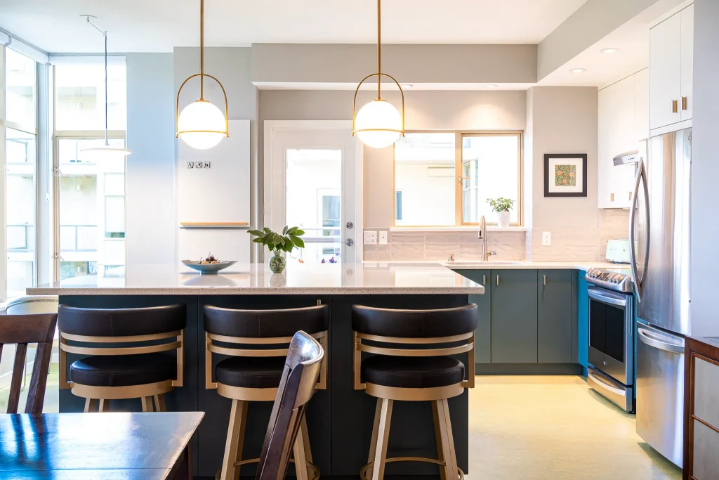 Modern kitchen with island, chairs, and pendant lighting.